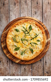 Freshly Baked Hot Delicious Four Cheeses Pizza With Cheddar, Mozzarella, Parmesan And Blue Cheese Garnished With Arugula And Basil Leaves Over Aged Wooden Background. Overhead View, Copy Space