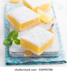 freshly baked lemon bars (or lemon  squares) with powdered sugar on white background, selective focus