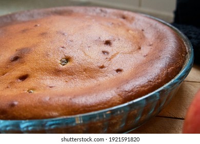 Freshly Baked Moist Quark Raisin Apple Cake In A Glass Mould On A Wooden Board With Apples On A Black Tea Towel