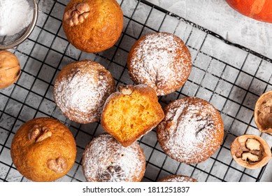 Freshly baked pumpkin muffins with walnuts, cinnamon and nutmeg on a baking rack, top view. Autumn or winter food. Sweet seasonal pumpkin baked goods. - Powered by Shutterstock