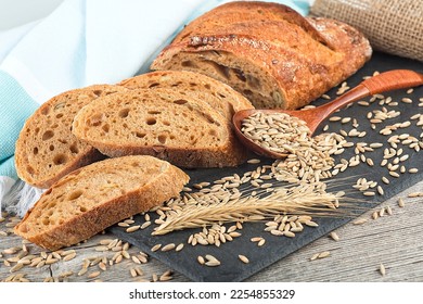 Freshly baked rye bread on wooden table. Whole grain rye baguette with seeds and spikelets. - Shutterstock ID 2254855329