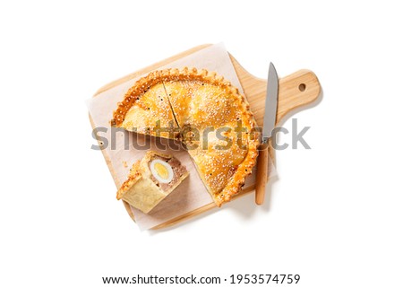 Freshly baked a showstopping raised pie using sausagemeat and boiled eggs isolated on white background, top view