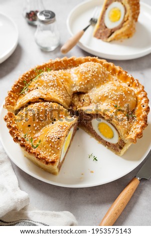 Freshly baked a showstopping raised pie using sausagemeat and boiled eggs on light gray background
