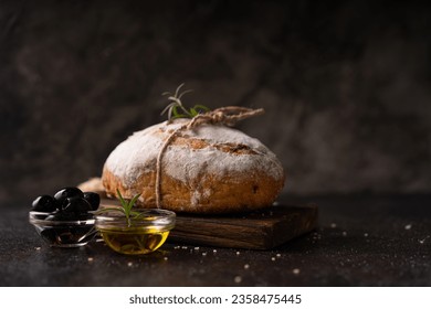 Freshly baked sourdough ciabatta bread with olives and rosemary on a black rustic table. Artisan bread - Powered by Shutterstock