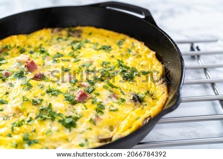 Freshly baked spinach and ham frittata in cast iron skillet.