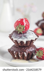 Freshly baked vegan chocolate muffins with red starwberries and white cream on a white plate. Gluten free dessert. Healthy breakfast concept.