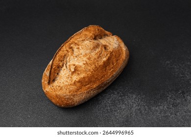 Freshly baked whole grain bread sits on a dark countertop, showcasing its crust.