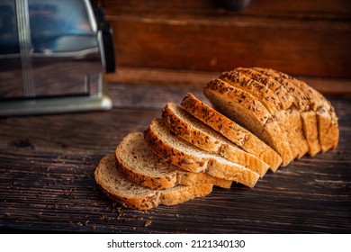 Freshly baked whole wheat flax and sunflower seed bread sliced on rustic wooden table with bread box and copy space.