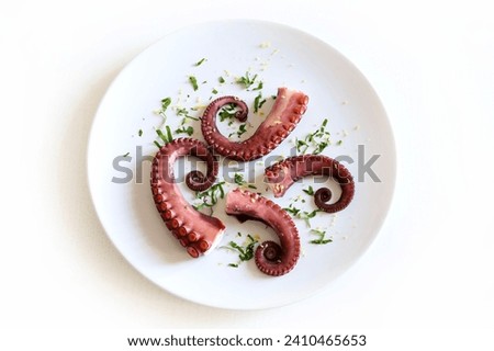 Freshly boiled octopus tentacles in a white plate with lemon zest and parsley. Seafood. Healthy food. Copy space. Overhead view.