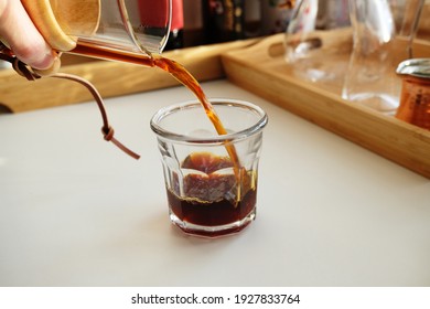 Freshly brewed black pour over coffee is poured into a glass. Alternative manual pour over drip brewing, specialty concept