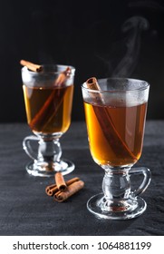 Freshly brewed black tea with cinnamon, in transparent cups on a dark background. - Shutterstock ID 1064881199
