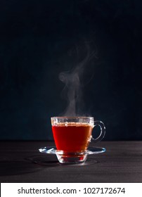 Freshly brewed black tea in a transparent glass Cup,escaping steam,darker background.
