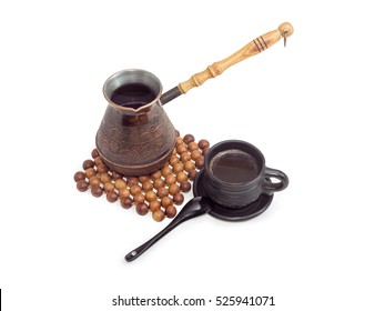 Freshly brewed black Turkish coffee in a old copper coffee pot on trivet, made of balls of juniper wood and in black ceramic cup on a light background
 - Powered by Shutterstock