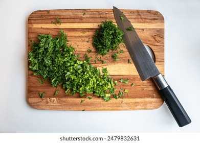 The freshly chopped herbs on a wooden cutting board with a chef's knife. - Powered by Shutterstock