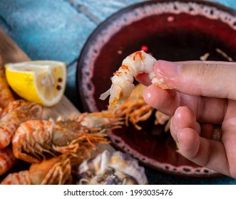 Freshly cooked chitin-free shrimp. A man holds shrimp meat over a plate.