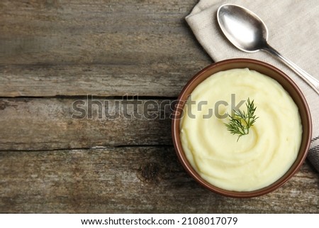 Freshly cooked homemade mashed potatoes with spoon and napkin on wooden table, top view. Space for text