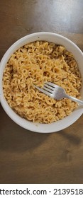 Freshly Cooked Ramen Noodles With Soy Sauce And Beef Sauce Packet Seasoning Closeup With Stainless Steel Fork In White Glass Bowl