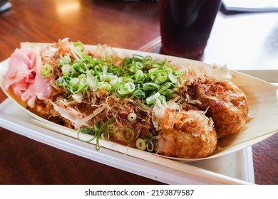 Freshly Cooked Takoyaki Ball-shaped Octopus Dumpling Served In A Paper Boat Tray With Bonito Flakes On Top. Famous Japanese Street Food Snack In Shinsaibashi Suji And Dotonbori Osaka Japan