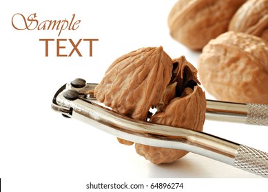 Freshly cracked walnut in nutcracker on white background with copy space.  Macro with shallow dof.