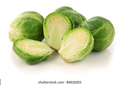 freshly cut brussel sprouts and some whole ones on a white background
