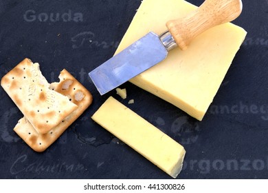 Freshly cut cheddar cheese with crackers on a slate board - Shutterstock ID 441300826