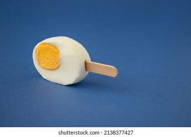 Freshly Cut Easter Egg With An Ice Cream Stick Against A Blue Background. Creative Food Or Holiday Concept.