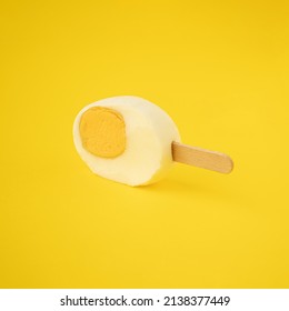 Freshly Cut Easter Egg With An Ice Cream Stick Against A Yellow Background. Creative Food Or Holiday Concept.