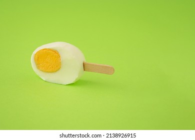 Freshly Cut Easter Egg With An Ice Cream Stick Against A Green Background. Creative Food Or Holiday Concept.