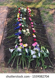 Freshly Dug Grave With Flowers Adorning It