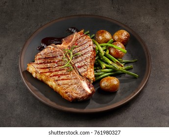 Freshly Grilled T Bone Steak And Vegetables On Dark Plate