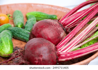 Freshly harvested beetroots with stems, cucumbers, and colorful cherry tomatoes in a rustic bowl, showcasing vibrant, organic produce. - Powered by Shutterstock