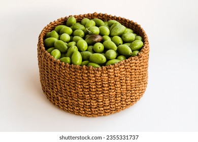 Freshly harvested green natural olives in wicker basket on white surface - Powered by Shutterstock