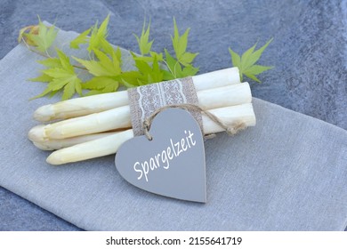 Freshly harvested white asparagus with the text Spargelzeit on a heart.Spargelzeit  is translated asparagus time.