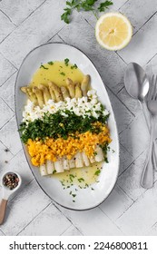 Freshly homemade white asparagus a la Flamande on a white plate. Flemish style white asparagus - with boiled eggs, parsley and hollandaise sauce
