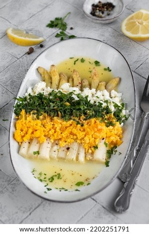 Freshly homemade white asparagus a la Flamande on a white plate. Flemish style white asparagus - with boiled eggs, parsley and hollandaise sauce