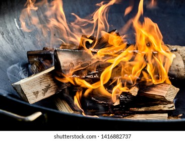 Freshly Lit Barbecue Fire With Logs Of Burning Wood Over Small Chips Of Kindling In A Portable BBQ