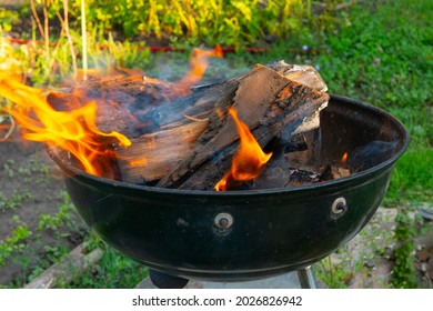 Freshly Lit Barbecue Fire With Logs Of Burning Wood Over Small Chips Of Kindling In A Portable BBQ