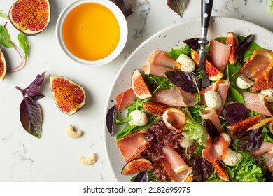 Freshly made Chopped Salad in Italian restaurant, mozzarella, figs, prosciutto or jamon. White marble background - Powered by Shutterstock