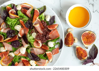 Freshly made Chopped Salad in Italian restaurant, mozzarella, figs, prosciutto or jamon. White marble background - Powered by Shutterstock