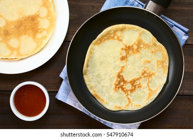 Freshly Made Crepe In Frying Pan With A Stack Of Crepes And Strawberry Jam On The Side, Photographed Overhead With Natural Light