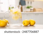 Freshly made lemonade in jug on white wooden table indoors