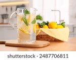 Freshly made lemonade with mint in jug on wooden table indoors