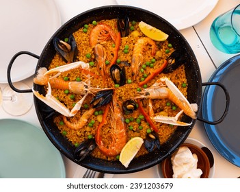 Freshly made seafood paella with lobsters, shrimps, calamari and mussels served in frying pan on table - Powered by Shutterstock