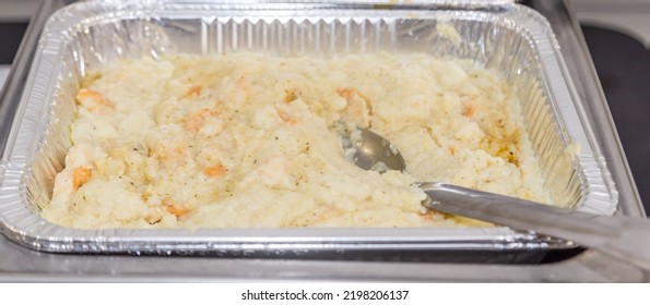 Freshly made shrimp and  grits in an aluminum foil pan being served a a brunch buffet. - Shutterstock ID 2198206137