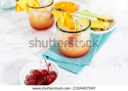 Freshly made Sunset cocktail garnished with a slice of fresh orange and pineapple.