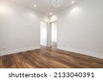 Freshly painted empty living room with dark wood floorboards and recessed lighting in the plaster