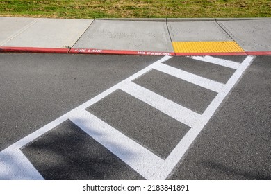 Freshly Painted White Crosswalk Marking Leading To A Yellow Painted ADA Sidewalk Access In A Fire Lane
