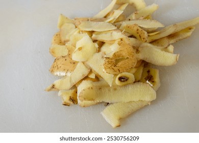 Freshly peeled potato skins scattered on a non-wooden cutting board, showcasing the rustic beauty of kitchen prep work. - Powered by Shutterstock