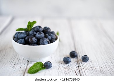 Freshly picked blueberries in bowl on wooden background. Concept for healthy eating and nutrition