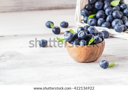 Freshly picked blueberries in wooden bowl.fresh blueberries with  leaves on a white rustic table. selective focus.